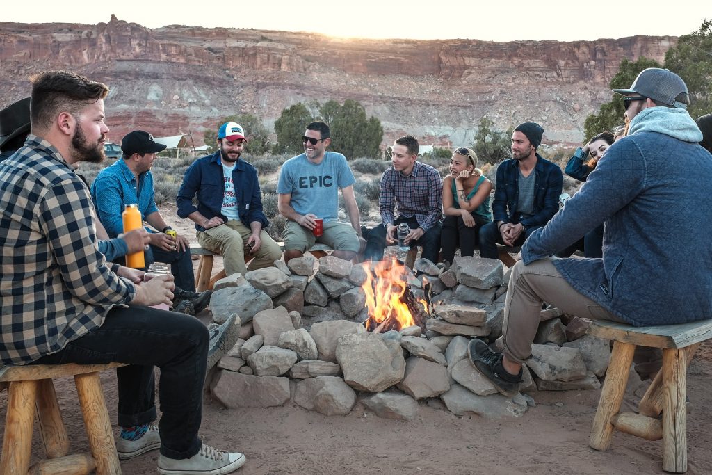 Happy friends sitting on rocks surrounding a camp fire